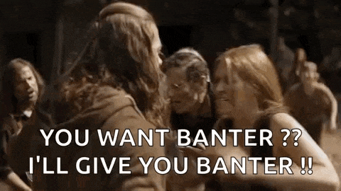 a man with long hair is talking to two women in a crowd of people .