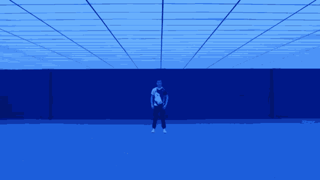 a man in a white shirt is standing in a room with blue lights on the ceiling