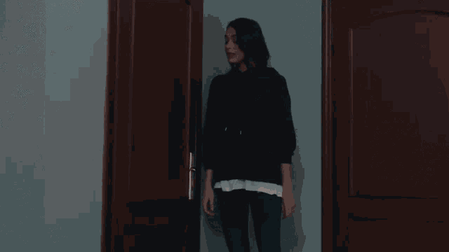 a woman in a black shirt stands in front of a door