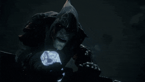 a monster with a hood on holds a glowing crystal