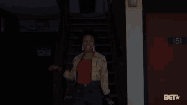 a woman is standing in front of a red door that says 151