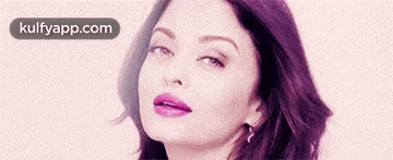 a close up of a woman 's face with purple lipstick and earrings .
