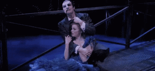a man in a mask is hugging a woman in a blue dress .