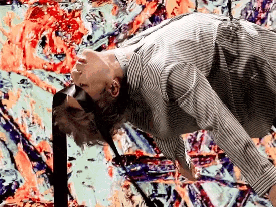 a man in a striped shirt is doing a handstand in front of a colorful background .