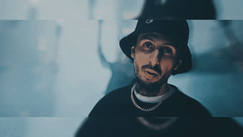 a man wearing a bucket hat and a chain around his neck has the letter g on his hat