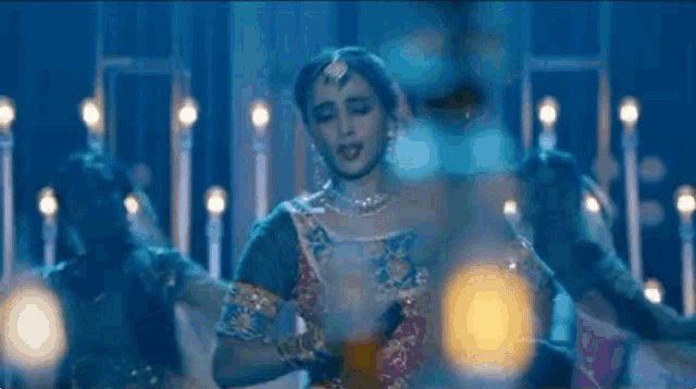 a woman in a sari is dancing on a stage in front of a crowd of people .