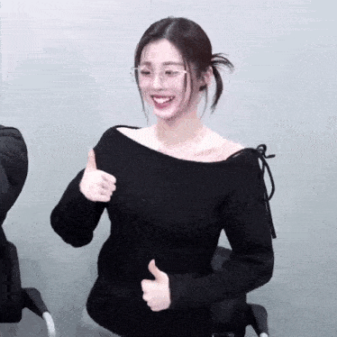a woman wearing glasses is giving a thumbs up