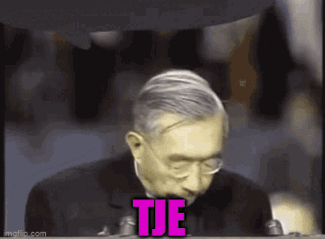 a man speaking into a microphone with the word tje written on the screen