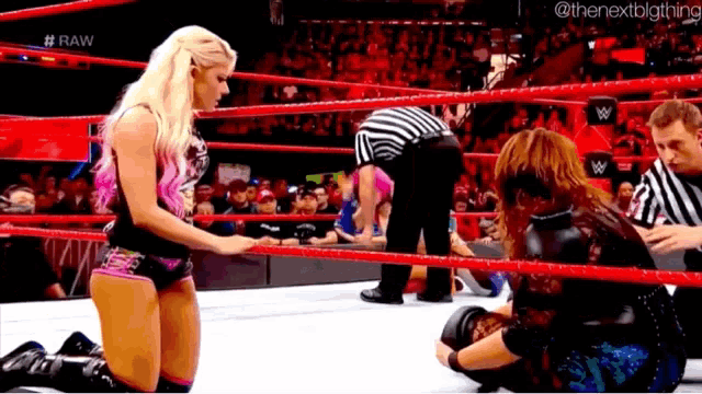 a woman kneeling in a wrestling ring with the word raw on the bottom right