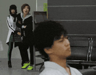 a group of people are standing in a room with a sign that says ' emergency exit ' on it