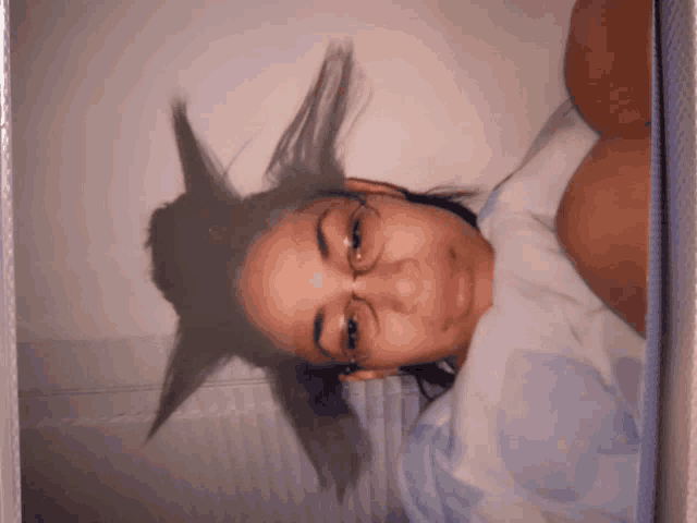 a woman wearing glasses is laying in bed