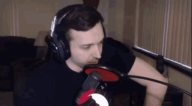 a man wearing headphones stands in front of a red microphone