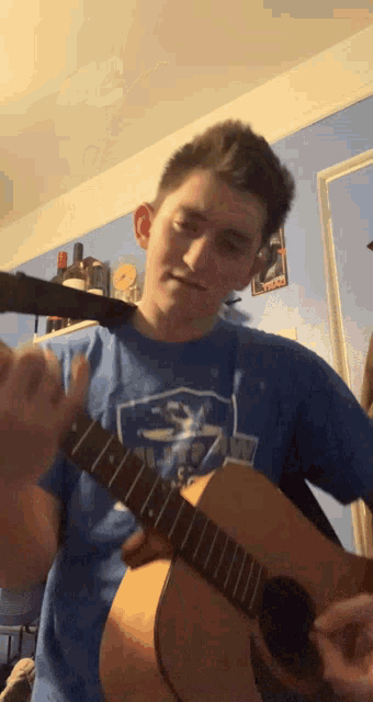 a man in a blue shirt playing a guitar