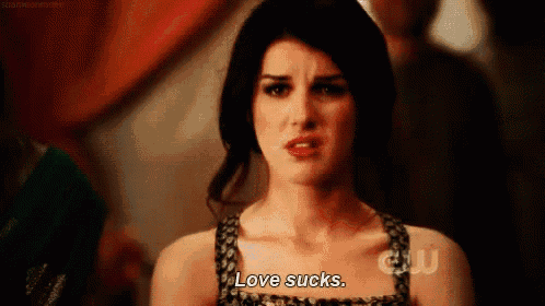 a woman is making a funny face and saying love sucks .