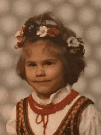 a little girl wearing a flower crown and a red necklace