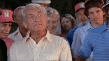 a man in a white shirt is standing in front of a crowd of people wearing hats .