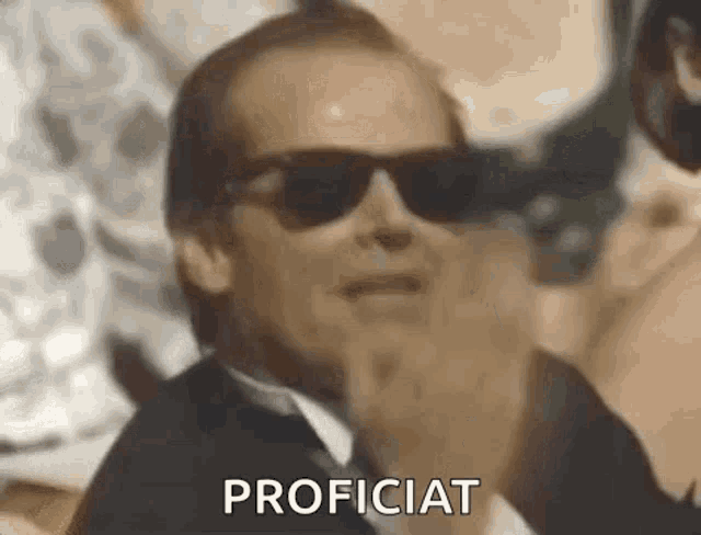 a man wearing sunglasses and a suit is making a funny face .