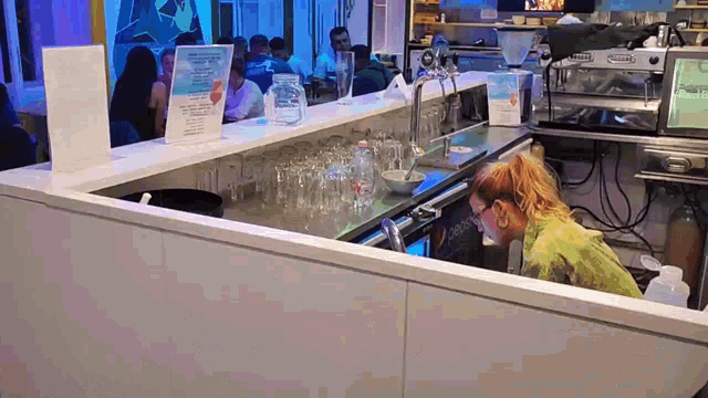 a woman is working at a bar with a sign on the counter that says ' caffe latte '