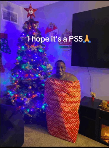 a man wrapped in a red blanket standing in front of a christmas tree