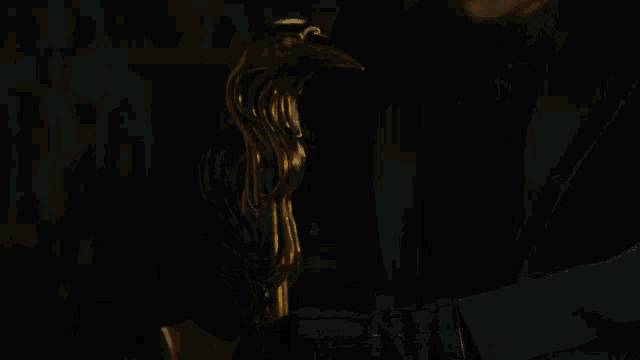 a man in a black suit is holding a gold object in his hand