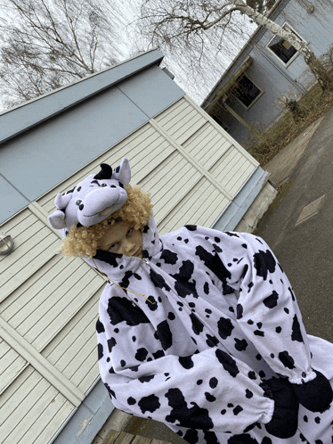 a person in a cow costume stands in front of a white building
