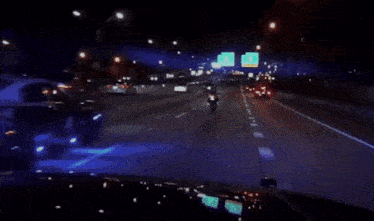 a police car is driving down a highway at night with a sign above it that says freeway