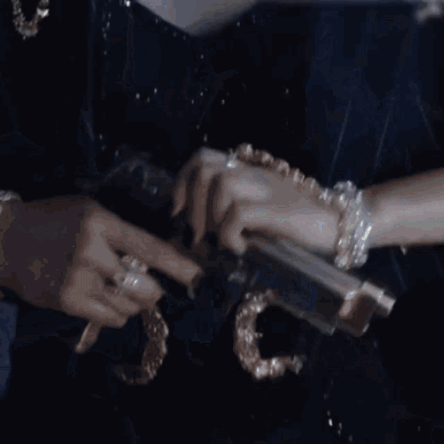 a woman in a black jacket is pointing a gun at someone