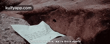 a piece of paper is laying on a rock with the words through the fire we 're born again written on it