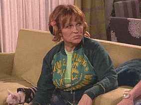 a woman is sitting on a couch with a cat and a green jacket on .