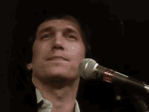 a man is singing into a microphone while wearing a hat .