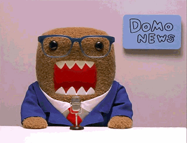 a stuffed animal wearing glasses and a suit is sitting in front of a sign that says domo news