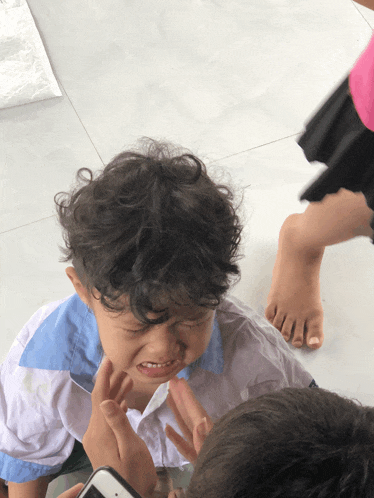 a little boy with curly hair is crying while being held