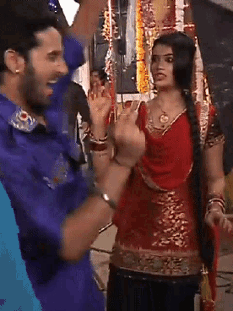 a man in a blue shirt and a woman in a red dress are dancing