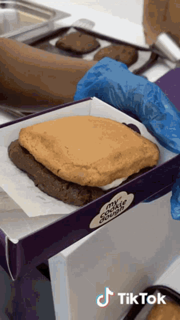 a person is holding a cookie in a box that says my cookie dough on it