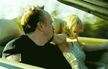 a man wearing an american flag shirt is driving a car with a woman