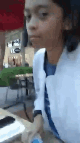 a young girl is sitting at a table with a cell phone in her hand .