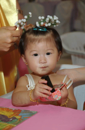 a little girl with flowers in her hair looks at something