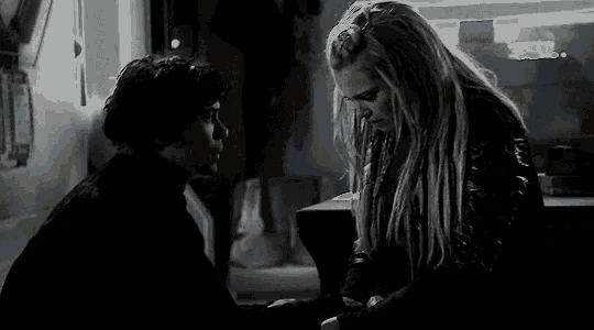 a man and a woman are standing next to each other in a dark room holding hands .