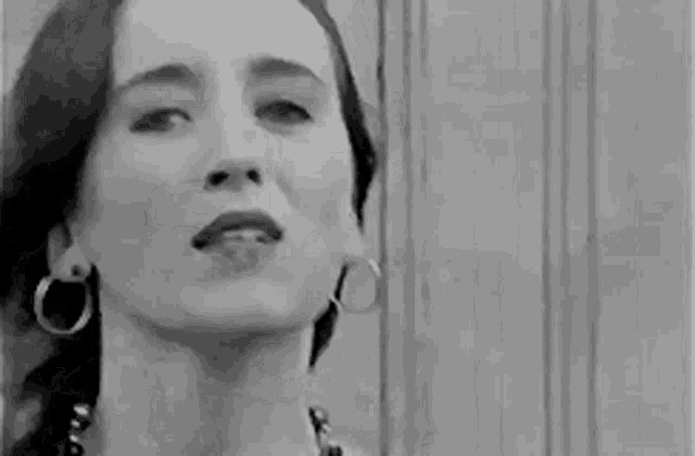 a black and white photo of a woman singing in front of a wall .