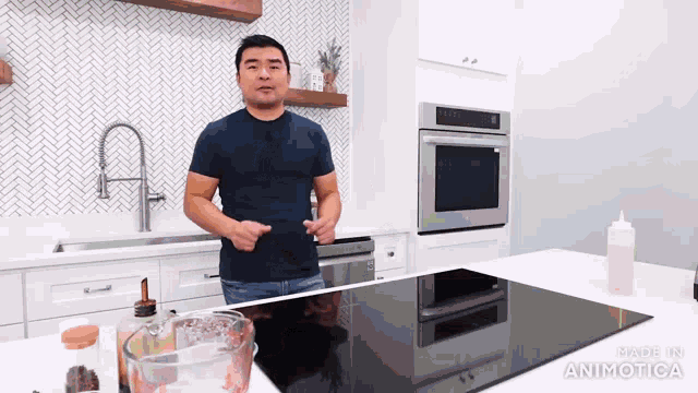 a man in a blue shirt is standing in a kitchen next to a black stove top oven