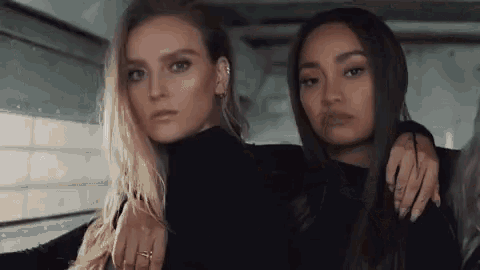two women are standing next to each other in a room .