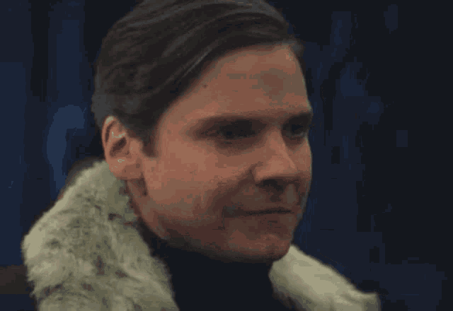 a close up of a man wearing a fur coat and a turtleneck .