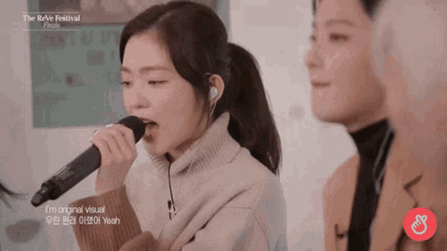 a girl is singing into a microphone while a man watches .