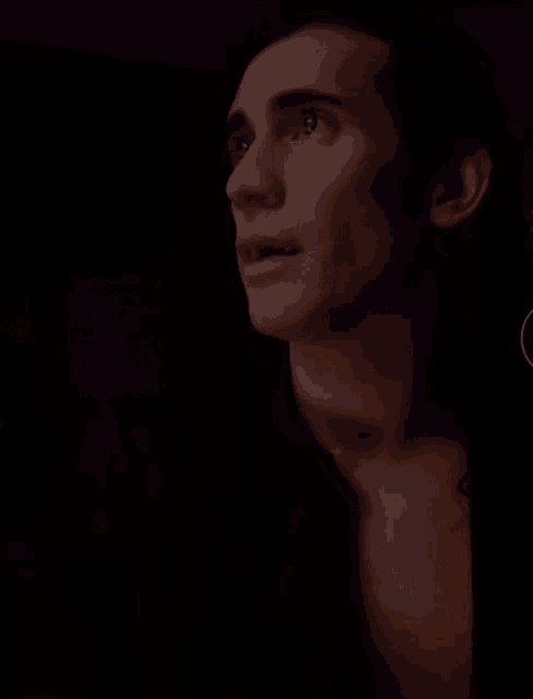 a man without a shirt is looking up at something in the dark