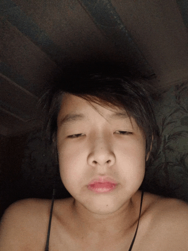 a young girl without a shirt is making a funny face with her eyes closed