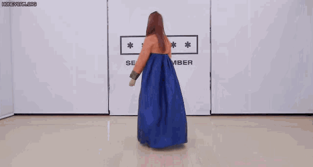a woman wearing a traditional korean dress is dancing in front of a wall .