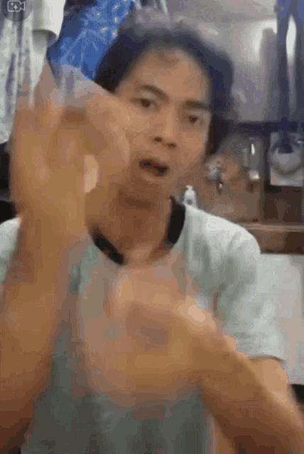 a man in a blue shirt is making a funny face while holding something in his hand