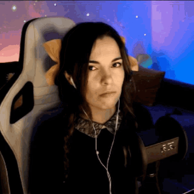 a woman wearing headphones and a bow in her hair is sitting in a gaming chair