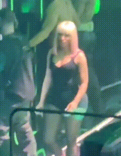 a woman with blonde hair is standing in a dark room with green lights