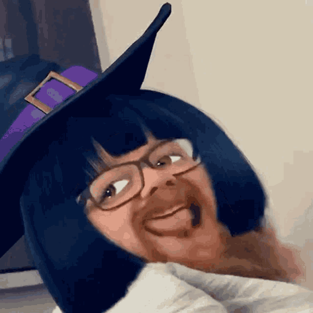 a woman wearing a witch hat and glasses is smiling